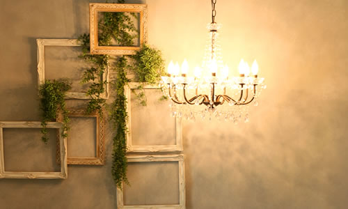 額縁を組み合わせたモチーフがかかる壁面にレトロなシャンデリアとの光があたる「マイブライド春日井」のスタジオイメージ