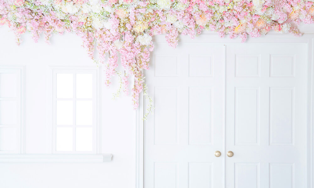 白い扉や窓を背景に、天井から下がる淡いピンクや白の花々で華やかな「マイブライド滝ノ水」のスタジオ風景