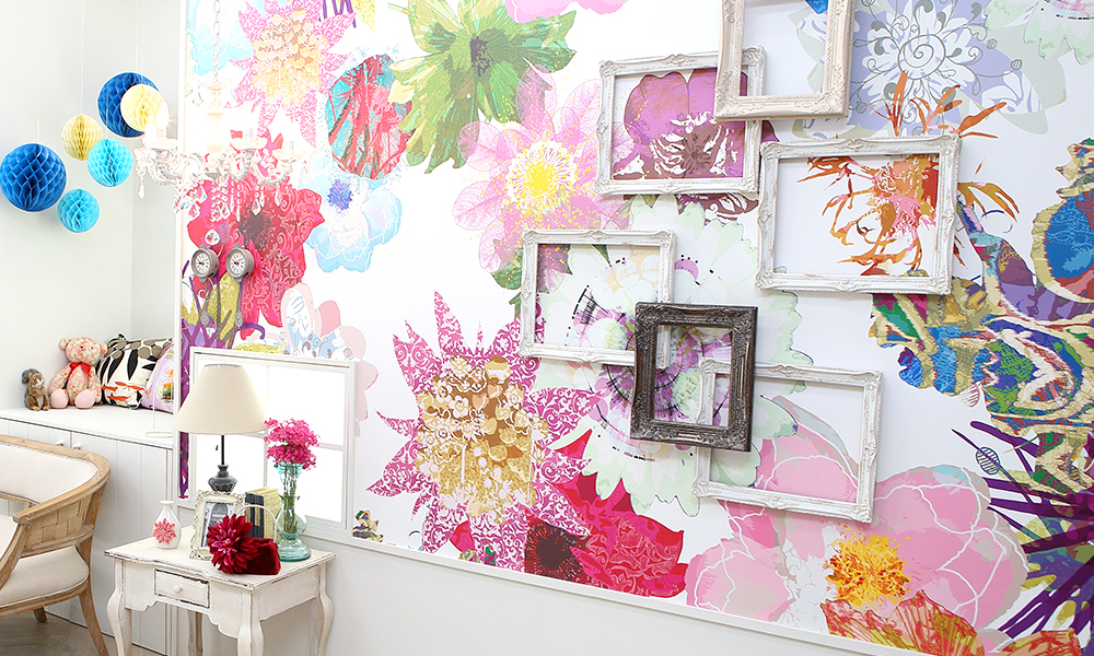 鮮やかな色の花々が描かれた壁に、いろんな額が飾られたアーティスティックな雰囲気のある「マイブライド尾張旭」のスタジオイメージ