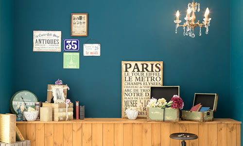 青緑の壁にレトロなポスター、本、小さなシャンデリアがる、あたたかみのある雰囲気の「マイブライド尾張旭」のフォトスタジオ