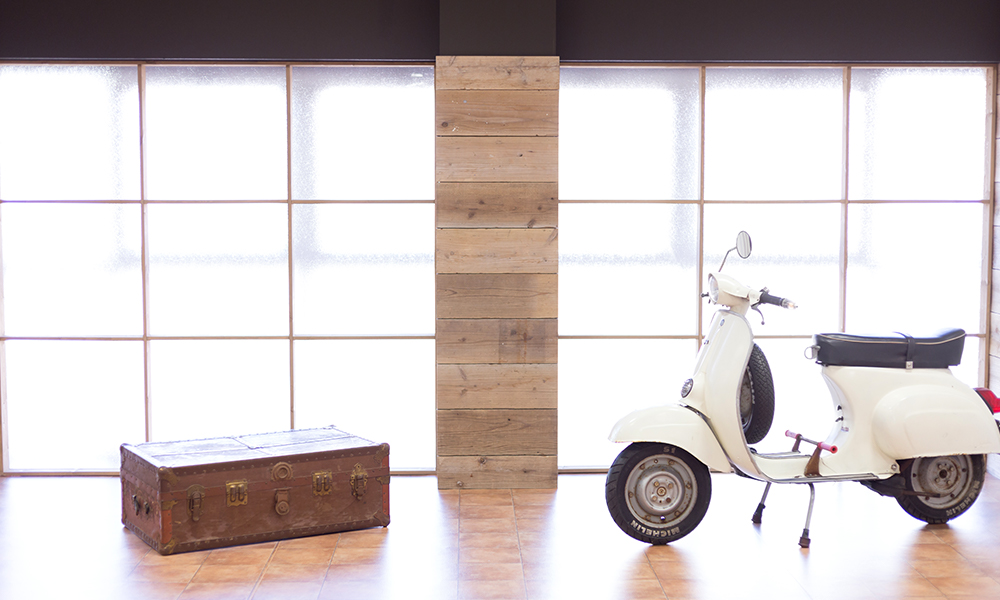 ウッド調の壁にレトロなバイク、トランクケースを配したカジュアルな洋風をイメージした「マイブライド豊明」のスタジオイメージ