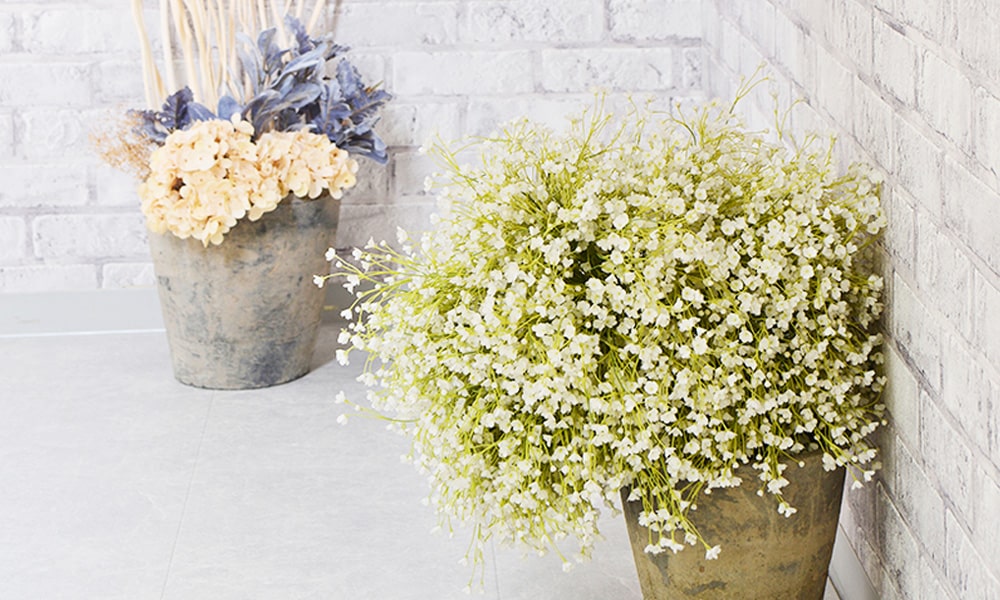 白いレンガ調の壁に淡い色味の花束が映える「マイブライド豊橋店」のスタジオイメージ