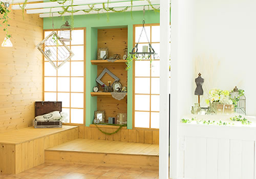 ウッド調で統一された壁面に明るいグリーンの差し色がある壁面に、レトロな雑貨を配したあたたかい雰囲気の「マイブライド一宮」のスタジオ