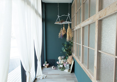 深い緑色の壁面に、ドライフラワーや雑貨が設置された北欧テイストの「マイブライド岡崎北」のスタジオイメージ